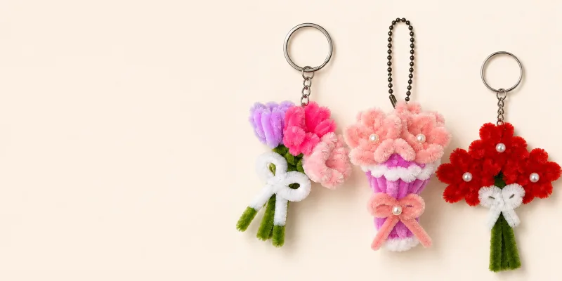 Two handmade chenille flower keychains, one lilac and one blush, beside a LEAP bouquet